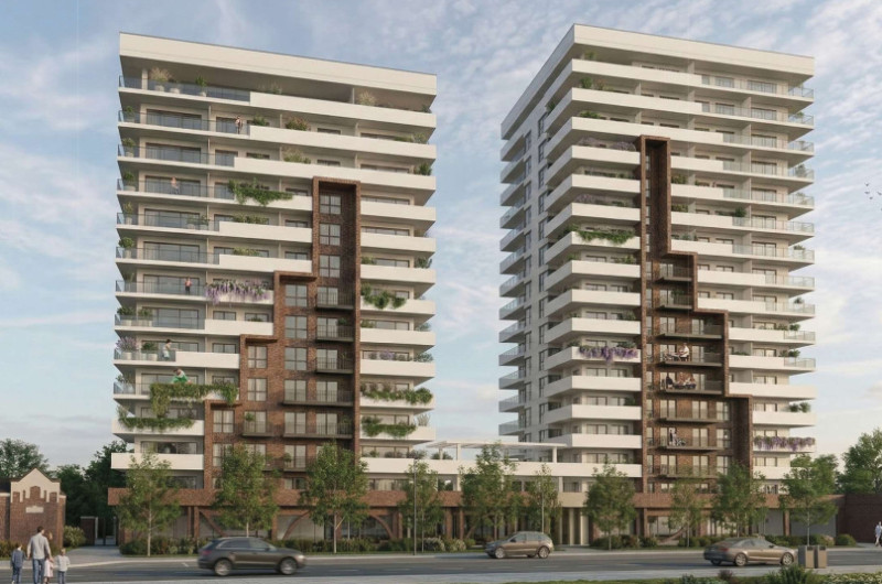 widok z ulicy na dwa 17 piętrowe budynki mieszkalne ze sklepami i kawarniami w parterze